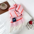 Detail of pink and orange striped wool blend scarf with white tassels on a bed - Large Label Style / Pink Orange (Striped)