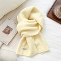 Detail shot of chunky knit texture on cream wool scarf with woven brand label - Yellow