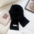 Detalle de la etiqueta de 100% lana y la marca en una bufanda de punto negra - Negro