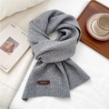 Detailed macro view of the grey ribbed knit scarf with a premium brown leather logo patch - 26*180cm / Light Gray