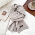 Detailed view of knitted scarf texture with premium brown leather logo patch on beige fabric - 26*180cm / White Coffee