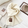 Close-up of thick cream wool knitted scarf with vertical ribbed texture and handmade label - Cream