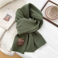 Close-up of army green ribbed knit scarf showing wool texture and leather tag detail - Green