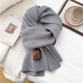 Close-up of thick light gray ribbed knit scarf with handmade leather brand label - Gray