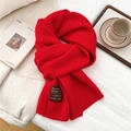 Detail of red ribbed knit wool scarf with handmade textile label on fabric surface - 185x30cm / Red
