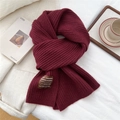 Close-up of thick rib-knit texture and handmade label on a warm wine red wool scarf - 185x30cm / Burgundy