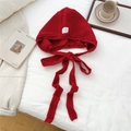 Flat lay of red knitted balaclava hood with long ties on white bedding lifestyle set - Red