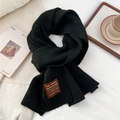 Detail of black knitted scarf with premium leather label on a cozy winter backdrop - One Size / Heathered Black