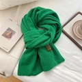 Gros plan détaillé sur la texture du foulard en tricot vert avec étiquette en cuir marron - 50*180cm / Vert