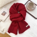Detalle de la bufanda de punto acanalado rojo oscuro con etiqueta blanca decorativa - Rayas Verticales Rojas