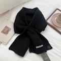 Close-up of black knitted cross scarf with button detail on white linen background - Black