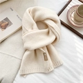 Detail of soft cream knitted scarf with ribbed edge and leather logo tag on white fabric - Milky White