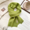 Detail of grass green knit scarf with ribbed edges and fabric label on soft white fabric - Green