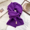 Detail of dark purple knitted scarf texture featuring plush fabric and woven brand label - Dark Purple