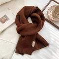 Detail of soft knit dark brown scarf with brand label on a cozy autumn setting - Brown