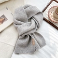 Close-up of gray knitted scarf showing ribbed edge and premium leather brand tag - Gray