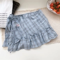 Detail of blue plaid wrap skirt featuring ruffled hem and side tie on woven mat - One Size / Light Blue Plaid