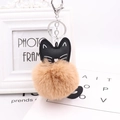 Close-up of black cat keychain with large beige faux fur pompom and silver metal hook - Khaki
