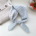 Light blue silky scarf with geometric patterns tied over a beige linen shirt - 27 Cyan Square Grid