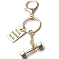 Gold fitness keychain with dumbbell pendant and engraved metal tag showing 'Strong' - Smooth Dumbbell and Tag Gold