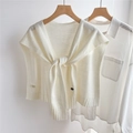 Trama in maglia dettagliata e bordo a coste di uno scialle in lana beige su camicia bianca - crema