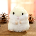 Cute cream and white plush hamster keychain toy on a rustic wooden surface background - Beige