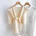 Detail shot of the 100% wool knit shawl tag and brand label on a cream shoulder wrap - Creamy White