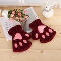 Nahaufnahme weinroter Plüsch-Katzenpfoten-Handschuhe mit rosa Polstern auf Holztisch - Burgunderrot