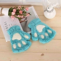 Close-up of blue plush fingerless gloves with cat paw embroidery on wooden background - Cyan