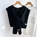 Detail of black knitted wool shawl tied over a white shirt on a wood hanger - Black