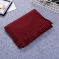 Thick burgundy cashmere-style scarf with elegant tassels displayed on a cozy grey surface - Burgundy