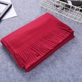 Folded red faux cashmere scarf with twisted fringe tassels on a soft grey surface - Burgundy