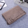 Thick light coffee cashmere scarf with fringe tassels on textured felt surface - Camel