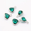 Macro shot of green crystal faceted triangle pendants with silver metal bezel setting - Dark Green