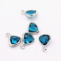 Detailed view of faceted dark blue birthstone charms with silver-plated metal bases - Lake Blue