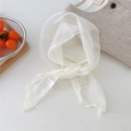Detalle de pañuelo blanco de gasa con bordes ondulados y etiqueta tejida ONE BAGEL - Beige