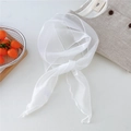 Detalle de bufanda de organza blanca con bordes enrollados sobre ropa de lino gris - Blanco