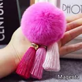 Detailopname van een rozerode bontpompon met drie roze kwastjes en gouden kapjes - 8cm / Rozerood