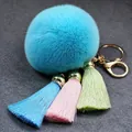 Detailweergave van een pluizige lichtblauwe kunstbont pompon sleutelhanger met zijden kwastjes - 8cm / Hemelsblauw
