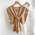 Detail of camel knitted shawl with cross-knot design over a white shirt for layering - Camel