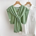 Close-up of green wool knit shawl with knot detail over a white shirt on wooden hanger - Light Green