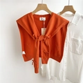 Close-up of bright orange knitted shawl wrap with decorative bows over a white shirt - 42*94cm / Orange
