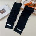 Close-up of black ribbed cooling arm sleeves featuring a white woven label and soft texture - One Size / Black