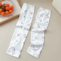Detail view of white sun protection sleeves with pink duck prints on a wooden desk - 03 Flower Pink Goose