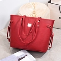 Macro view of red lychee leather texture and metallic logo plate on the large tote bag - Wine Red