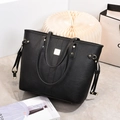 Detail of black pebbled leather tote bag featuring gold hardware and slim top handles - Black