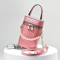 Dettaglio borsa cilindrica rosa coccodrillo con tracolla in oro e manico di perle - Rosa
