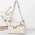 Detail of quilted texture, gold metal lock, and white plush charm on a pink handbag - Off White