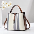 Minimalistische gestreifte Canvas-Handtasche mit braunem Leder auf weißem Tisch - Grauweiß