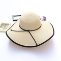 Detail of beige straw sun hat with black trim and ribbon on white background - Beige